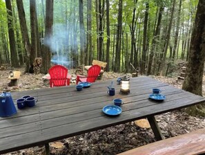 Enjoy a casual meal in a serene forest setting, surrounded by tall trees and a warm lantern.
