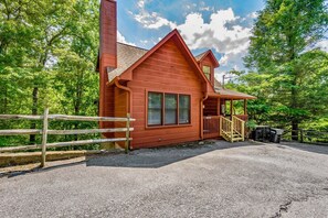 Eine Holzhütte mit Veranda, Treppe und einem Schotterweg.