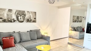En moderne stue med en grå sofa, et gult sofabord og billedkunst på væggen.