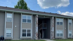 A two-story building with a brick entrance and a small outdoor staircase. - The Ingrid - Entire 2 Bedroom Apt in Quilt Town, USA (Hamilton)