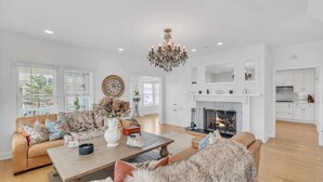 A spacious living room with a fireplace, a chandelier, and a sofa set.
