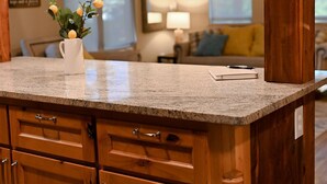 A kitchen with wooden cabinets, granite countertops, and pendant lighting.