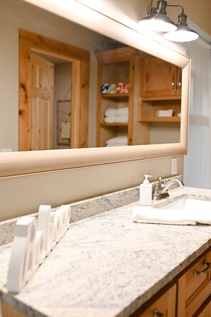 Un baño con encimera de granito, lavamanos, espejo y toalla.