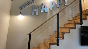 A staircase with wooden steps and metal railings, leading to a landing where the words "CHOOSE HAPPY" are displayed in metallic letters.