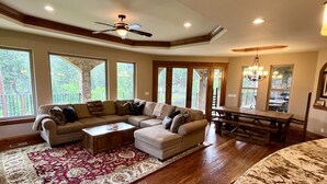 A spacious living room with a sectional sofa, a coffee table, and a dining area with a wooden table and chairs. - Riverfront Mansion with Indoor Pool, Private Pond, and Hot Tub on 16 Acre Ranch (Hamilton)