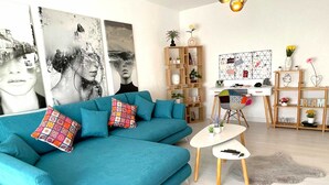 A modern living room with a teal sofa, a coffee table, and a bookshelf.