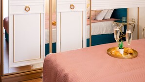 A bedroom with a bed, a bedside table with two glasses of water, and a tray with croissants.