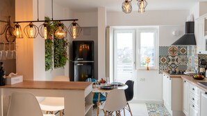 A modern kitchen with a dining area, featuring a black refrigerator, a wooden countertop, and a patterned backsplash.