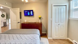 Un dormitorio con cama, cómoda, televisor montado en la pared y ventilador de techo.