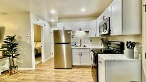 Una cocina moderna con armarios blancos, electrodomésticos de acero inoxidable y piso de madera.