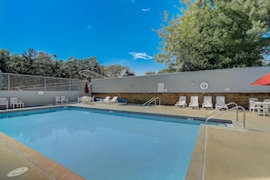 A swimming pool with lounge chairs and a covered area.