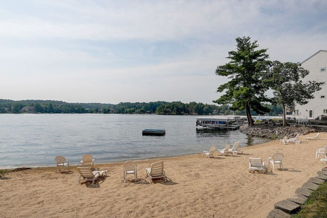 Une plage avec des chaises longues et une jetée qui s’avance dans l’eau.