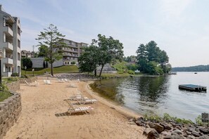 A beach with sun loungers and a dock by a lake, surrounded by buildings. - Brown Family Condo - Top Floor Views - Boat Slip (Wisconsin Dells)