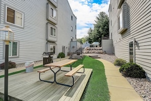A residential area with a wooden deck, picnic table, and a well-maintained lawn.