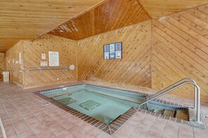 Puisesti sisustettu tila, jossa on poreallas, laatoitettu lattia ja puuseinät.