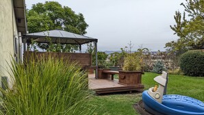 Een terras met een houten dek, een overdekte zithoek en een opblaasbaar zwembad.