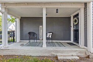 A porch with two chairs, a welcome sign, and a wreath on the door.