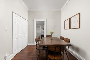 Een eetkamer met een houten tafel, stoelen en een bloevas.