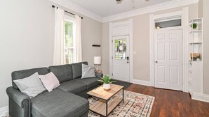 A living room with a grey sofa, a wooden coffee table, a patterned rug, and a ceiling fan.