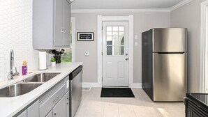 A modern kitchen with stainless steel appliances, a double sink, and a sign indicating 'DOWNTOWN'.