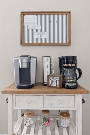 A coffee station with a coffee maker, a mug rack, and a sign that says 'HELLO COFFEE'.