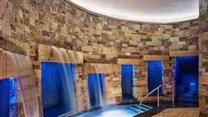 A spa area with stone walls, a curved pool, and multiple water features.