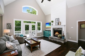 Cozy living room with a fireplace, comfortable seating area, and a view of the surrounding greenery.