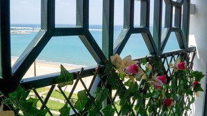 A view through a geometric window frame with a beach and ocean in the background. - Lovely and clean Apartment (TANGER)