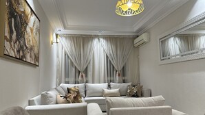 A modern living room with a sofa set, a marble coffee table, and a large abstract painting on the wall. - Lovely and clean Apartment (TANGER)