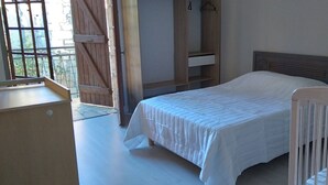 A bedroom with a bed, a wooden wardrobe, and a small table.
