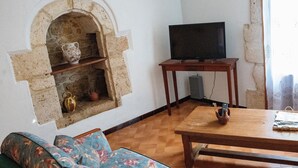 A living room with a stone fireplace, a sofa, a wooden coffee table, and a television on a stand.