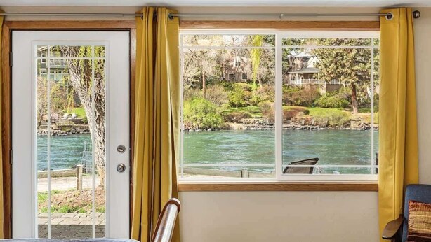 A room with a view of a river, a door, and a window with curtains. - Pet Friendly Cottage on the River near Downtown! (Bend)