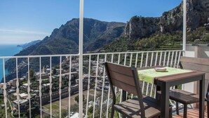 A balcony with a table and chairs, overlooking a coastal town and mountains. - Positano: Villa Mamma Rosa with spectacular sea views over the Amalfi Coast (Positano)