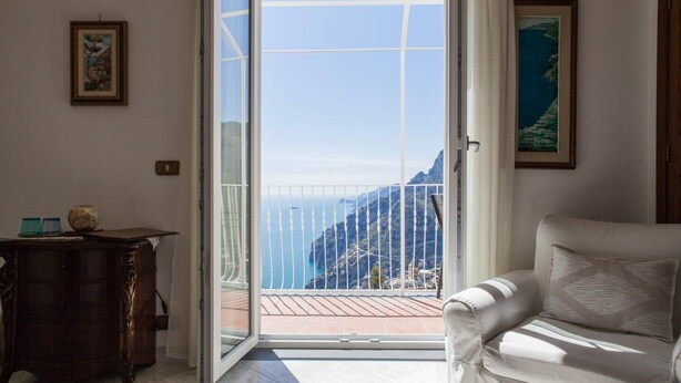 A room with a large sliding glass door leading to a balcony with a mountain view. - Positano: Villa Mamma Rosa with spectacular sea views over the Amalfi Coast (Positano)