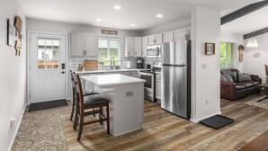 A modern kitchen with white cabinets, stainless steel appliances, and a central island. - Immaculate 3 bedroom with hot tub , AC , close to golf course , Whitefish lake , Whitefish Trails! (Whitefish)