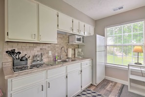 Kitchen features a microwave, coffee maker, and sink, with a window and lamp nearby.