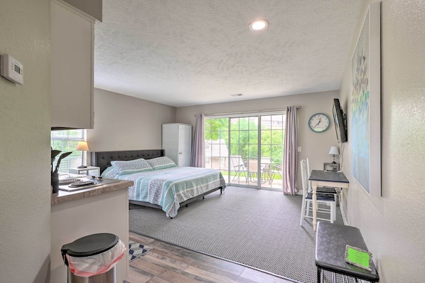 Relax in a cozy space with a large bed against a window, a compact desk for work, and a ceiling fan for ventilation.