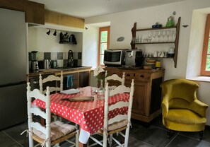 A kitchen with a dining table, chairs, a microwave, and a yellow armchair.
