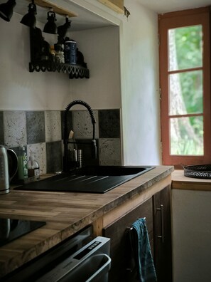 A kitchen with a black sink, wooden countertop, and a window with a view of greenery. - A vacation home nestled in the heart of a 14th-century ironworks and surrounded by breathtaking natural beauty. (Campôme)