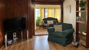 Una sala de estar acogedora con paredes de madera, un sofá verde, un mueble de televisión negro y una estantería.