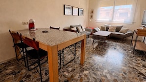 A living room with a tiled floor, a dining table with chairs, a sofa, and a television. - City center apartment perfect for couples in Barcelona (Barcelona)