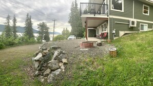 A house with a balcony, a fire pit, and a car parked outside. - Dancing Waters Lakehouse - Semi Waterfront - Shuswap Vacations and Sledding Accommodation (Anglemont)