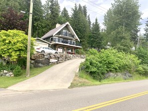 A two-story house with a stone retaining wall and a driveway leading to the entrance.