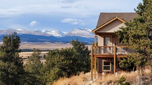 Una cabaña con terraza con vistas a un paisaje montañoso.