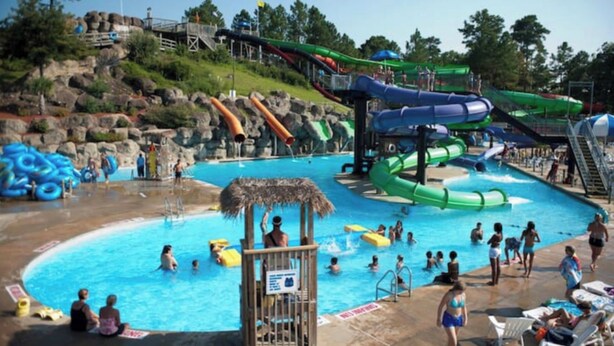 A water park with multiple water slides, a swimming pool, and a lifeguard station. - Oceanfront 3-BR boardwalk condo w indoor pool! (Virginia Beach)