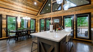 Una cocina amplia con una isla grande, paredes de madera y ventanas grandes que ofrecen vistas al exterior.