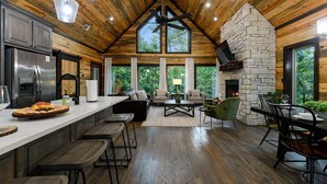 Una cocina amplia con una isla grande, una chimenea de piedra y un comedor con vistas al exterior.
