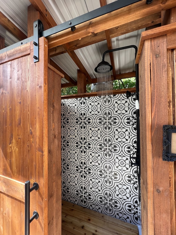 A wooden structure with a patterned tile wall and a metal door. - Riverfront Cabin! BBQ, HOT TUB, FIRE PIT, 4 BEDROOMS (Baring)