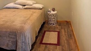 A bedroom with a bed, a small bedside table, an air conditioner, and a television mounted on the wall. - Country Charm (Williamson)