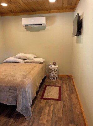 Cozy retreat with a single bed, bedside table, and air conditioning unit.